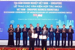 Le secrétaire général du Comité central du Parti communiste du Vietnam, Tô Lâm, supervise l'échange des documents de coopération lors d'une table ronde des affaires Vietnam-Singapour, à Singapour, le 13 mars. Photo: VNA