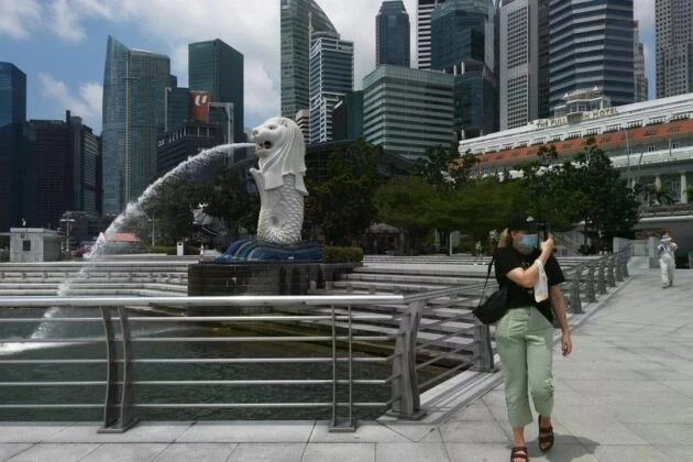 Un touriste portant un masque visite le parc Merlion à Singapour (Photo : capitalfm.co.ke)