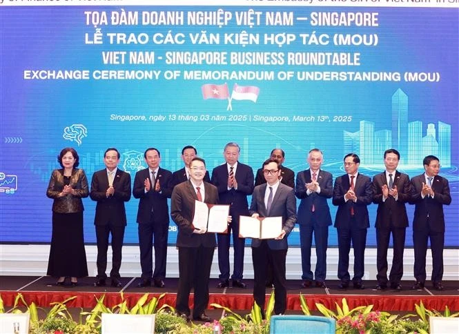 Le secrétaire général du Comité central du Parti communiste du Vietnam, Tô Lâm, supervise l'échange des documents de coopération lors d'une table ronde des affaires Vietnam-Singapour, à Singapour, le 13 mars. Photo: VNA