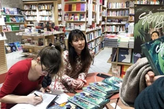 Hai Anh (droite) et Pauline Guitton dédicacent leur ouvrage à des lecteurs en France. Photo: tuoitre.vn