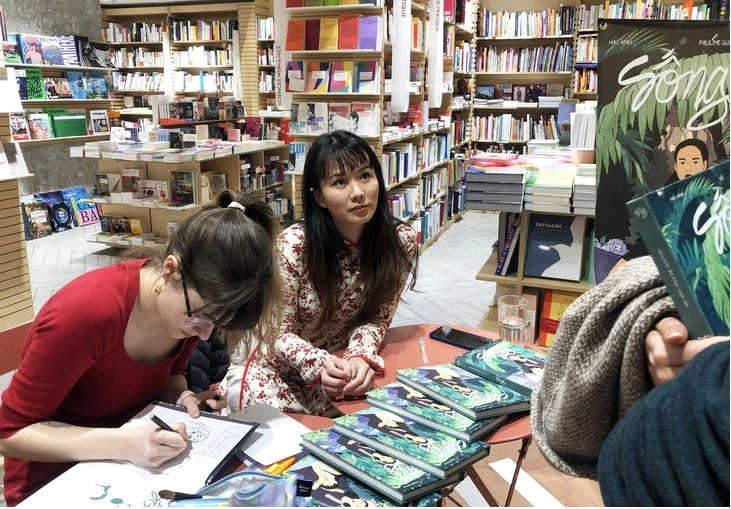 Hai Anh (droite) et Pauline Guitton dédicacent leur ouvrage à des lecteurs en France. Photo: tuoitre.vn